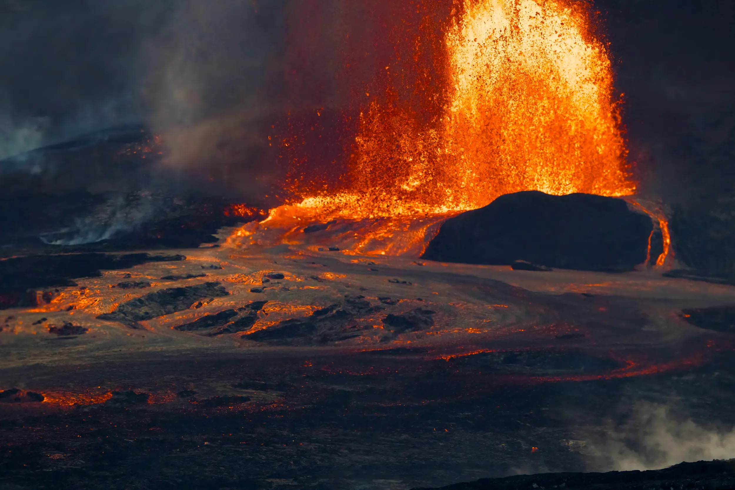 Lave en éruption au parc national des volcans d'Hawaii, une fontaine orange incandescente sur la roche sombre
